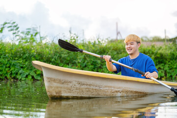 Joyful man tourists rowing boat with oars in river. Travel, vacation holiday and outdoor activity.