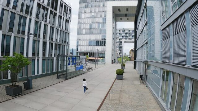 Woman walk between old and modern buildings in Cologne's Rheinauhafen District, slow moton aerial shot