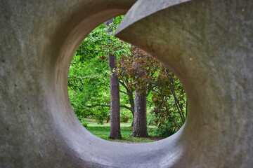 Close up of abstract art stone eye with lush green forest visible through tunnel hole