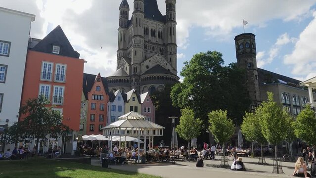 Aerial view of tourists in park in front of church Gross St Martin with unique colorful houses in the old town of Cologne, Germany, slow motion