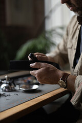 Man doing leatherwork, in a leather working workshop, making a black leather belt