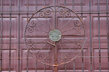 Southern Pacific lines rusty metal gate in front of maroon garage doors close up