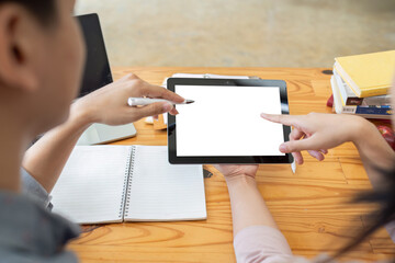 Mockup image of two student holding black tablet with blank desktop white screen while study at table in livingroom