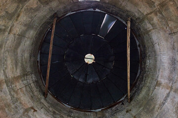 Interior of concrete silo with black camera shutter like roof or ceiling