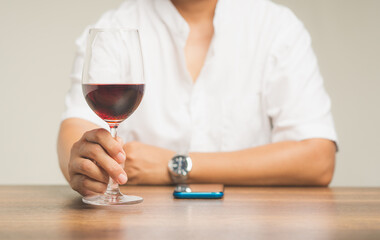 Businessman holding a glass of red wine while sitting at the table.