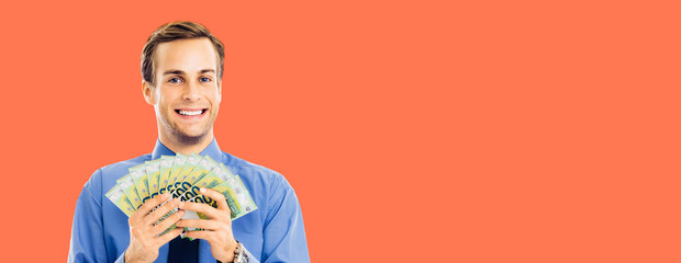 Portrait of smiling businessman holding money, euro cash banknotes, isolated over bright vivid orange color background. Confident happy man at studio. Copy space for text. Wide banner composition.