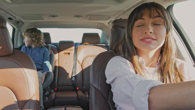 Young Family Of Mother Driver And Boy Ready To Move In Car To School And Using Child Back Seat. Male Kid Looks Outside And Joyful Woman Talking With Son While Driving, Adventure With Positive Emotion.