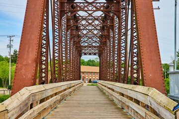 Tall beams reaching up from old rusty railroad bridge converted into wooden walking bridge