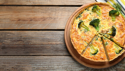 Piece of delicious homemade quiche with salmon and broccoli on wooden table, top view. Space for...