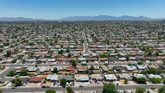 Sprawling suburb of city. Aerial truck shot over thousands of houses and homes in desert housing development. Middle class people commute into large USA city to work. Mountain range in background.