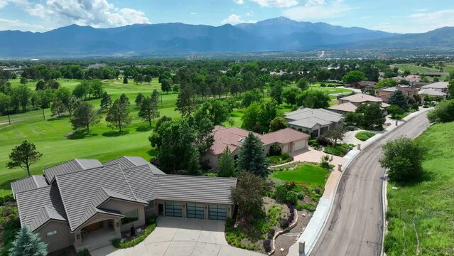 Colorado Springs country club neighborhood. Private housing development of mansions on golf course with beautiful view of Rocky Mountains in CO. Aerial establishing shot of houses and homes.