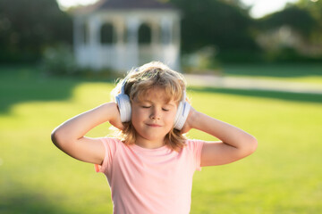 Lovely child enjoying music through headphones. Expressing true positive emotions of fashionable happy child. Portrait of kid in headphones listening music with closed eyes. Daydreaming child.