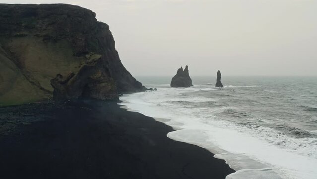 Cinematic Aerial Drone Shot of Black Sand Beach of Reynisfjara, Vik - Iceland. Sharp Cliffs Coastline