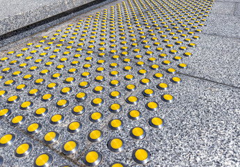 gray granite staircase with yellow tactile indicators for visually impaired people