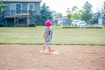 Young girl running to second base after a hit with dust coming up from the field. 