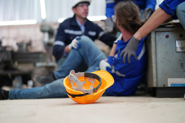 Worker receiving industrial injury in factory and colleague helping him while  injured on leg.