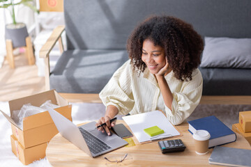 Startup SME small business entrepreneur of freelance African woman using a laptop with box Cheerful success African woman her hand lifts up online marketing packaging box and delivery SME idea concept