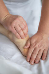 Fototapeta premium Close-up of man doing foot massage on white background. Reflexology foot massage. Tired feet concept. Vertical
