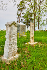 Three large tombstones, etchings in stone, graveyard headstones, summer trees and grass