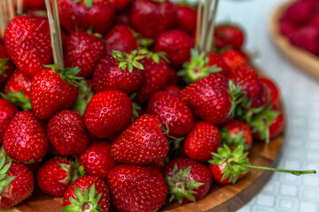Many fresh strawberries on a wooden serving plate on the table. Vitamins and health Close-up.