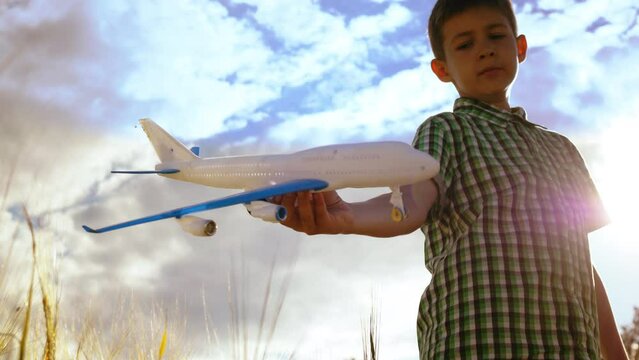 Skyward Adventures: Boy's Playtime with Toy Airplane in Sunny Summer Weather, Against a Backdrop of the Sky