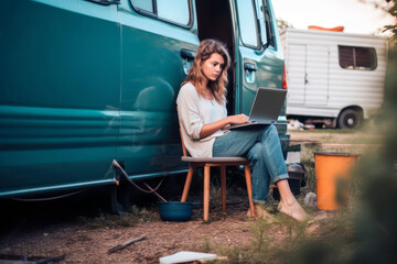 Young woman digital nomad engaging in remote work outside her vintage camper van, epitomizing the mobile, van life lifestyle, generative ai