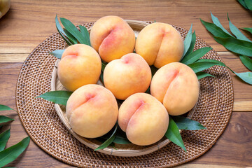 Yellow Peach on wooden basket,  Peach with leaf on wooden background.