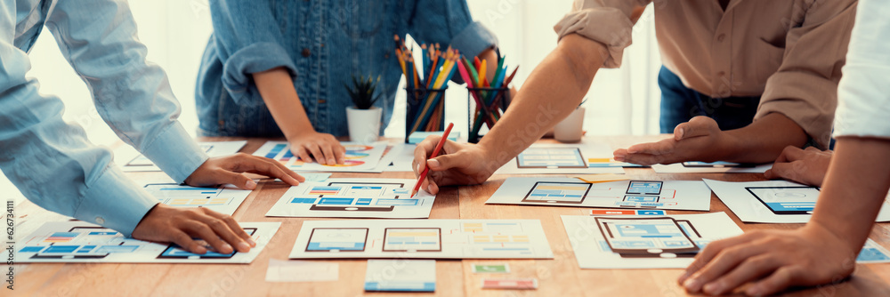 Poster Panorama shot of front-end developer team brainstorming UI and UX designs for mobile app on paper wireframe interface. User interface development team planning for user-friendly UI design. Scrutinize