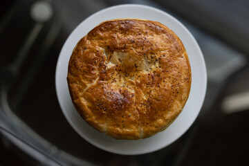 Home made chicken pot pie on a glass table next to a window at sunset