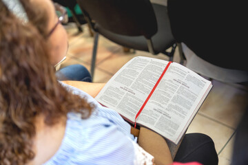 Naklejka premium Mujer de buen aspecto latina con cabello ondulado sosteniendo la biblia en una iglesia