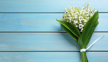 Beautiful lily of the valley bouquet on light blue wooden table, top view. Space for text
