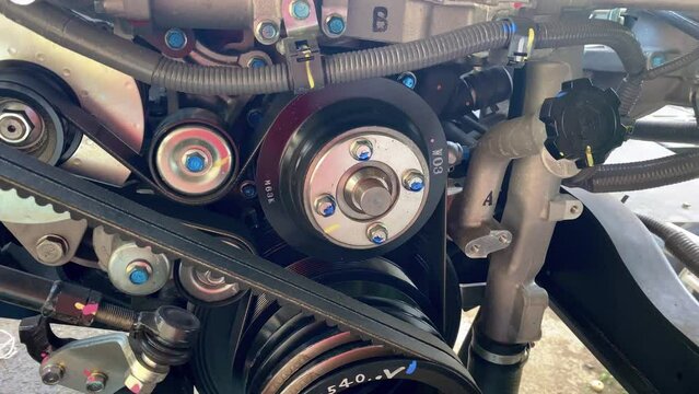 Tension belt and v-belt installed on machine. Close up detail of the vehicle engine fragment. Belt and pulley drive.