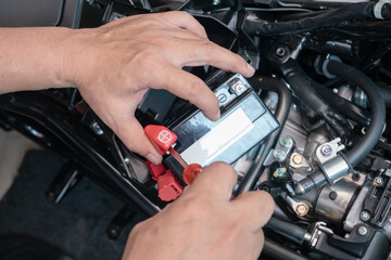 Mechanic remove the battery terminal open with a screwdriver, and takes the battery out of the motorcycle to charge,motorcycle maintenance and repair concept . selective focus