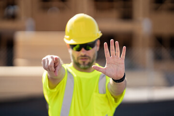 Construction site worker in helmet working outdoor. A builder in a safety hard hat at constructing buildings. American wooden house in beams, wood frame structure, framing construction.