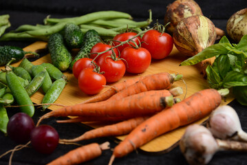 fresh vegetables from the vegetable garden on a wooden board on a black background, macro
