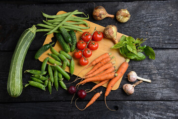 fresh vegetables from the vegetable garden on a wooden board on a black background
