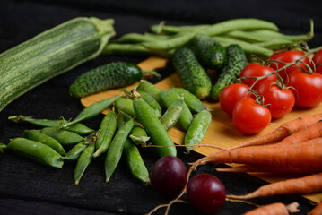 fresh vegetables from the vegetable garden on a wooden board on a black background, macro photo
