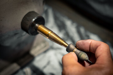 Goldsmith polishing a gold ring jewel in his jewelry workshop. Jeweler hands working in his craftwork studio.