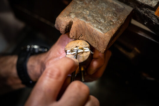 Jeweler hands setting a diamond into a ring with a burin. Goldsmith working creating a gold jewel in his jewelry workshop.