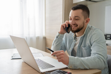 man working and speaking at laptop doing a phone call. home job office lifestyle alternative business Caucasian businessman work online on computer talk with client or customer on cellphone.