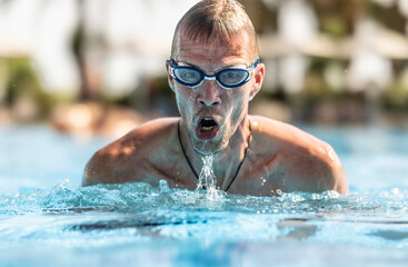 A male swimmer swims breaststroke in a swimming pool during training for a triathlon