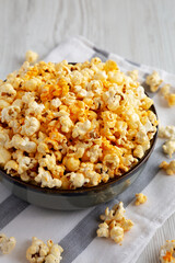 Homemade Pop Corn with Cheese in a Bowl on a white wooden background, side view. Close-up.