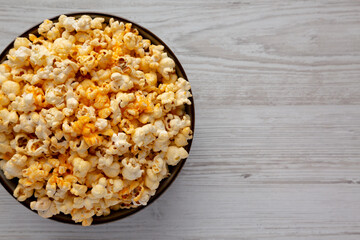 Homemade Pop Corn with Cheese in a Bowl on a white wooden background, top view. Flat lay, overhead, from above. Copy space.