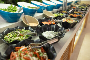 Salads with fresh vegetables in bowls on the buffet table in the hotel restaurant