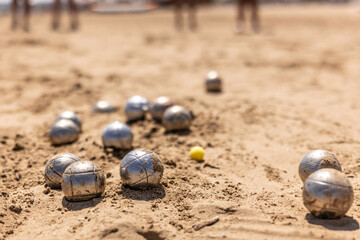 Petanque balls in the sand by the sea during a game on the beach