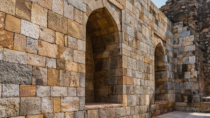Fototapeta na wymiar Ruins of the ancient temple complex Qutub Minar. Brick wall with arched niches. Delhi. India.
