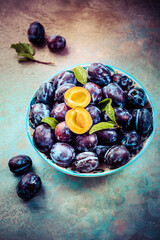 Fresh plums on plate over dark stone background