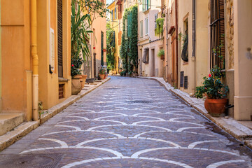 Ornate mosaic street pavement between traditional old houses near the covered provencal farmers market in old town or Vieil Antibes, South of France
