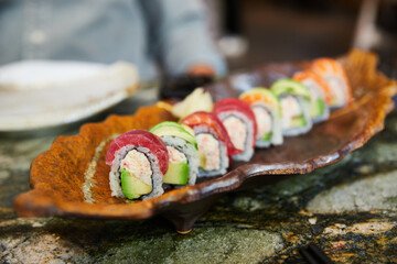 Rainbow Uramaki en restaurante japonés. Sushi de surimi y aguacate recubierto de salmón, atún y aguacate. 