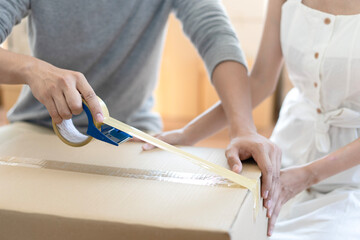 Couple of young asian helping pack machine, sealing cardboard boxes and delivery to customer at home. Startup small business entrepreneur or freelance Couple asian, Shipping delivery and SME concept.